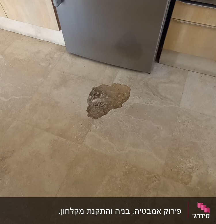 רצפה עם כתם רטיבות ליד מקרר נירוסטה